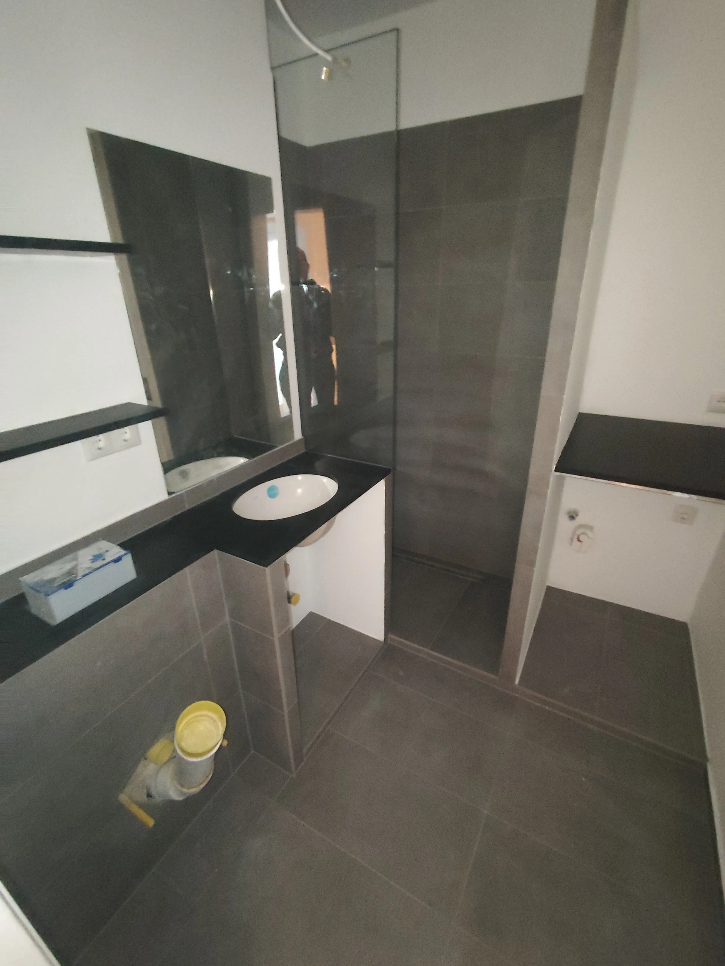 Modernes Badezimmer mit grauen Fliesen, Dusche und Waschtisch