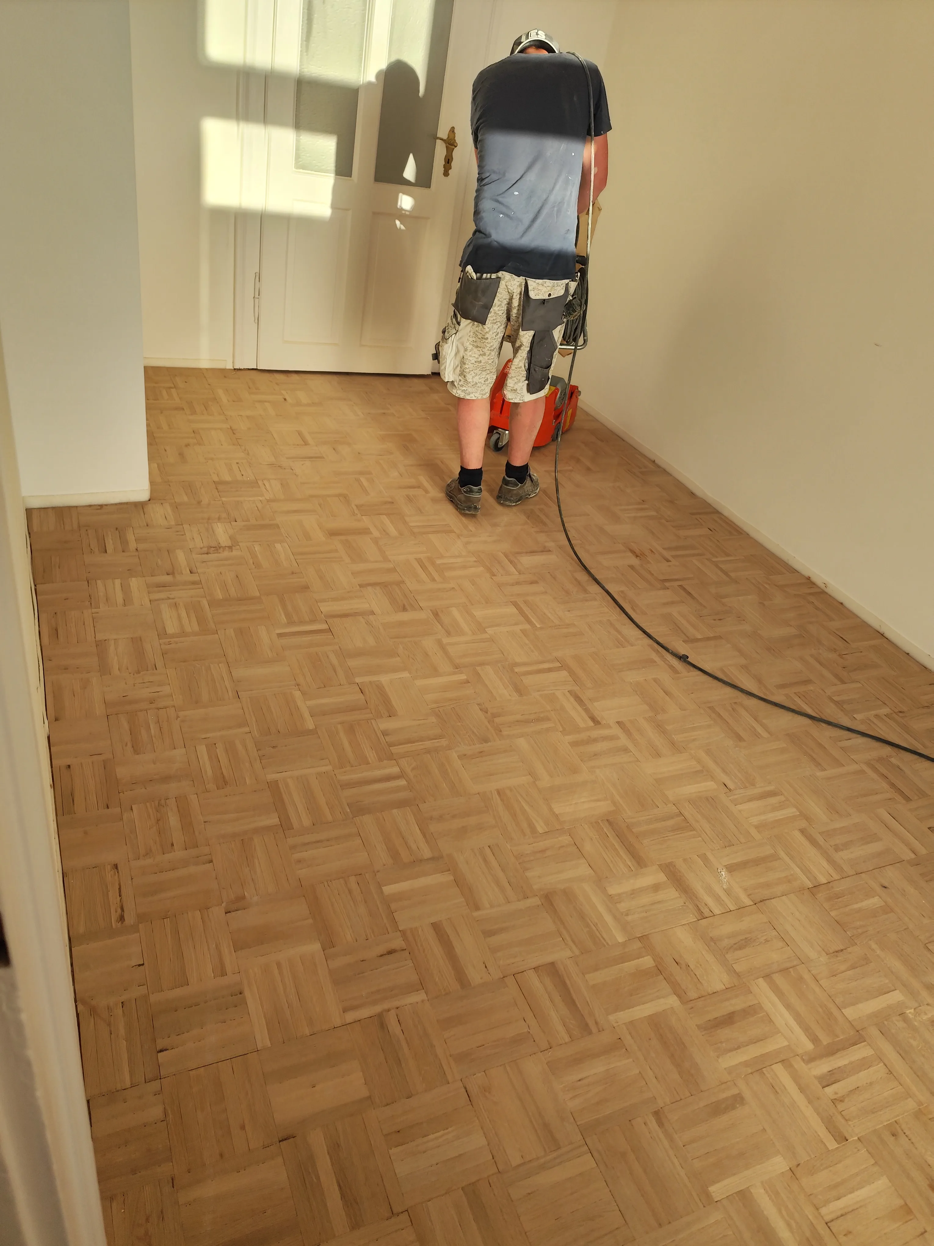 Arbeiter beim Verlegen von Parkett in einem Raum mit hellem Boden