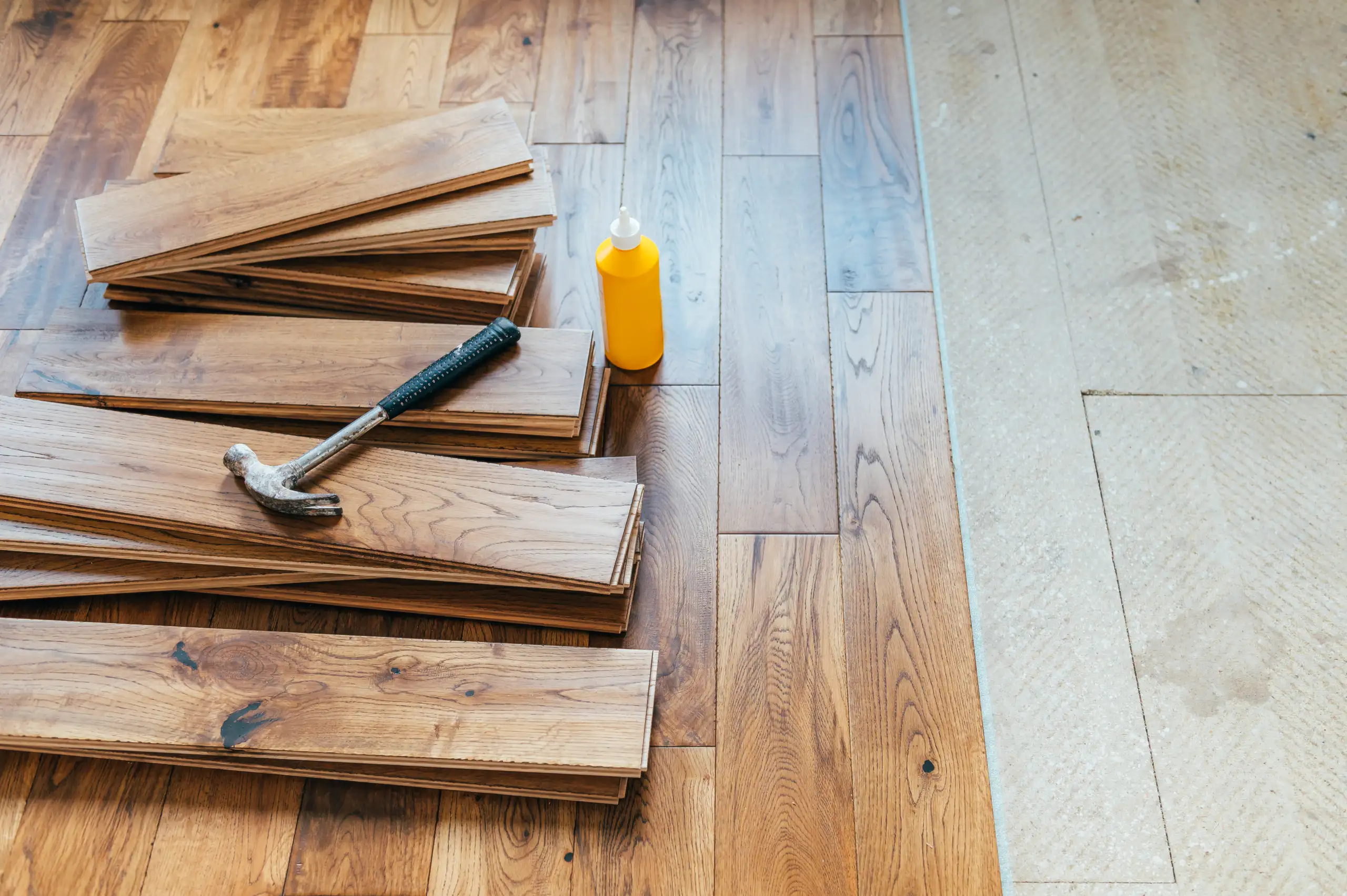 Holzplatten für die Bodenverlegung liegen auf einem Holzboden mit Werkzeug