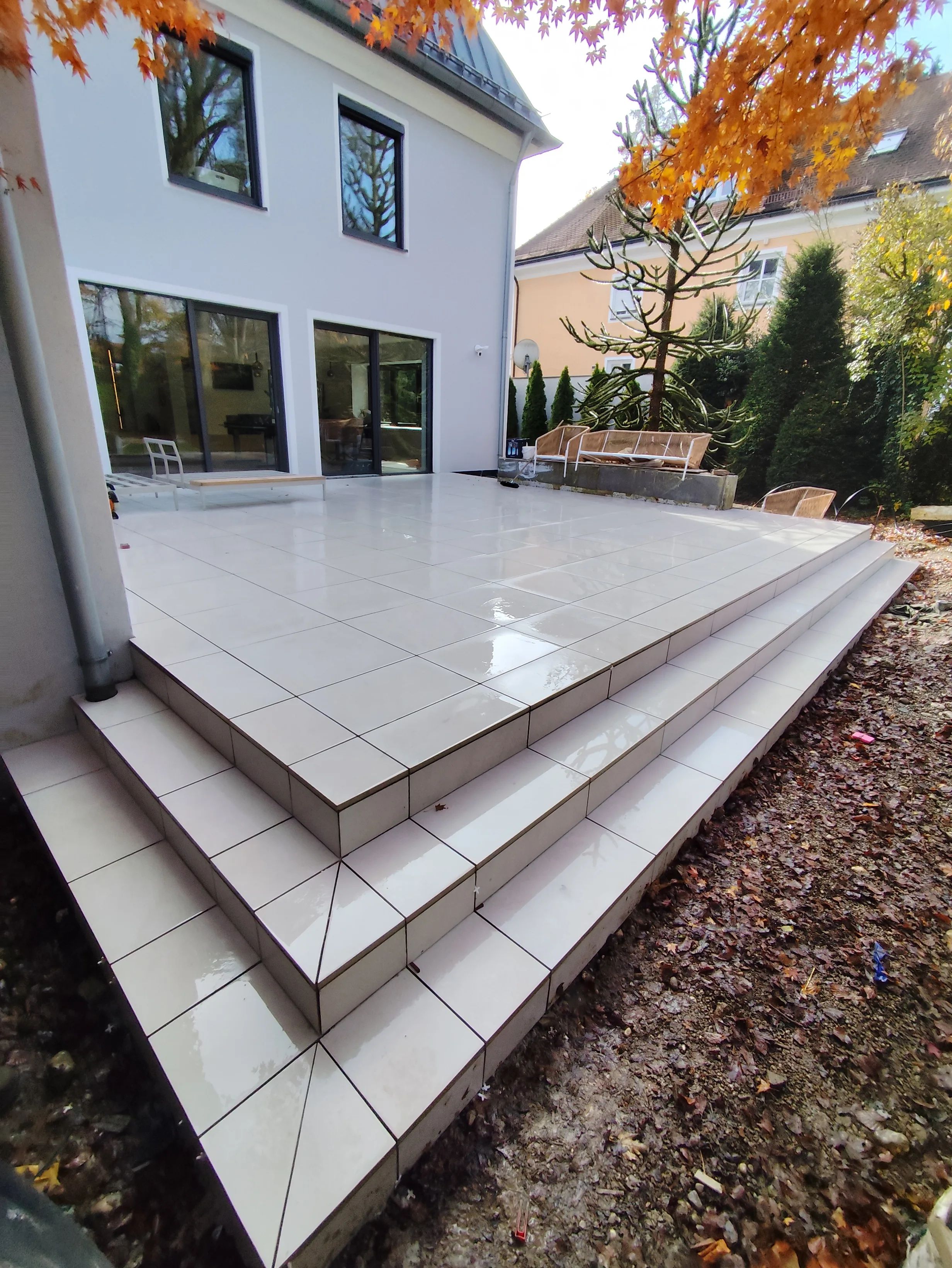 Terrassenfläche mit großen Fliesen und Stufen in einem modern gestalteten Außenbereich