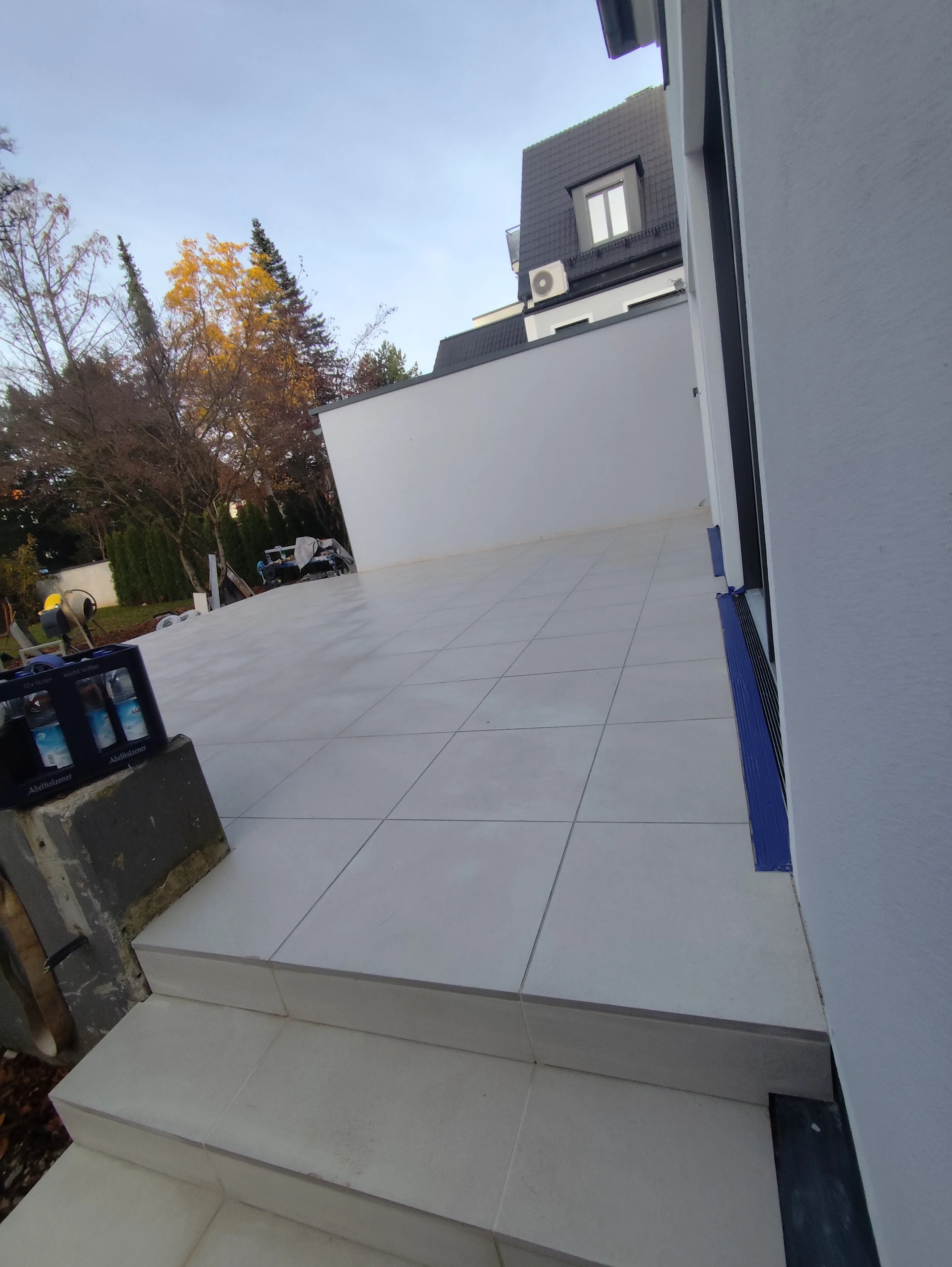 Terrasse mit großen Fliesen und Treppenaufgang zur Wohnung