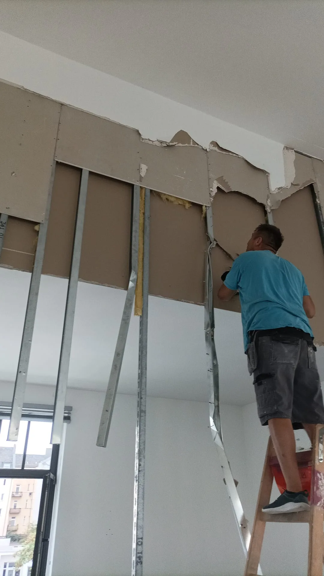 Ein Handwerker installiert Gipskartonplatten für den Trockenbau in einem Innenraum