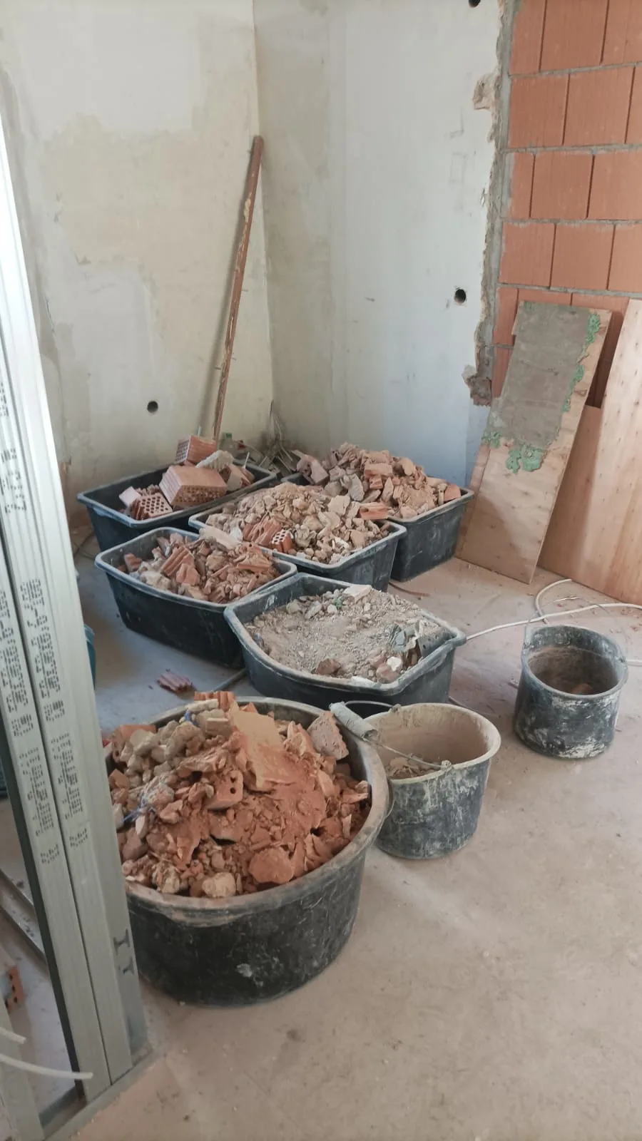 Baustelle mit mehreren Eimern voller Bauschutt und renovierungsbedürftigen Materialien