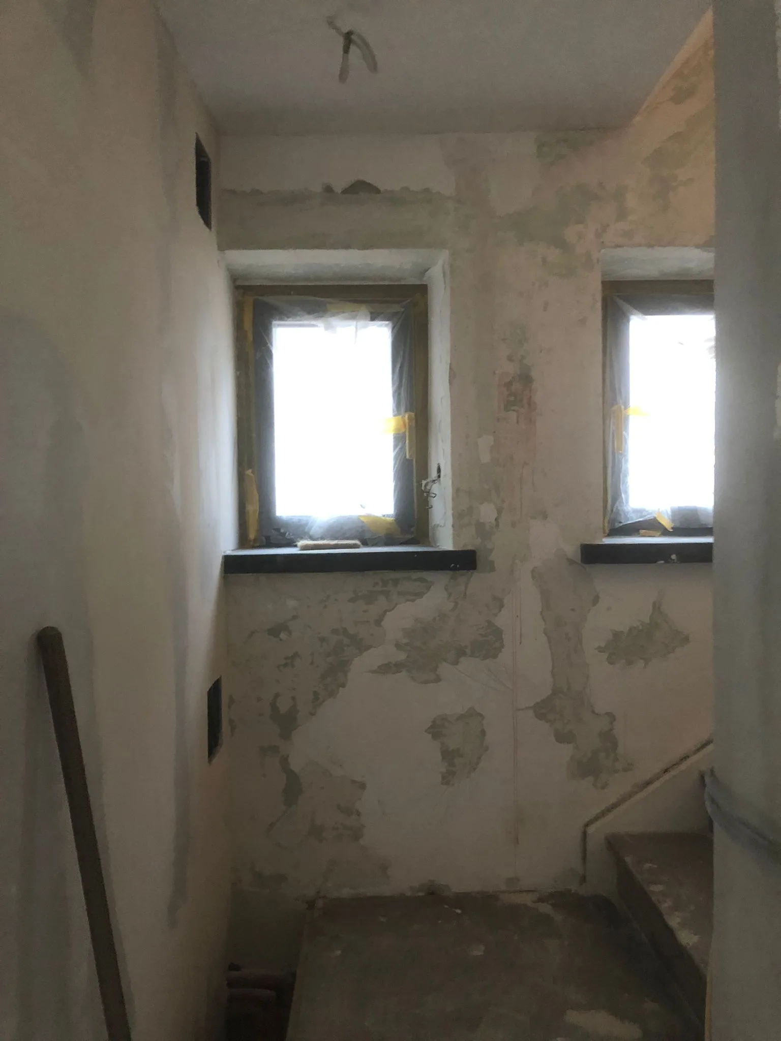Innenansicht eines renovierungsbedürftigen Raums mit beschädigten Wänden und Fenstern