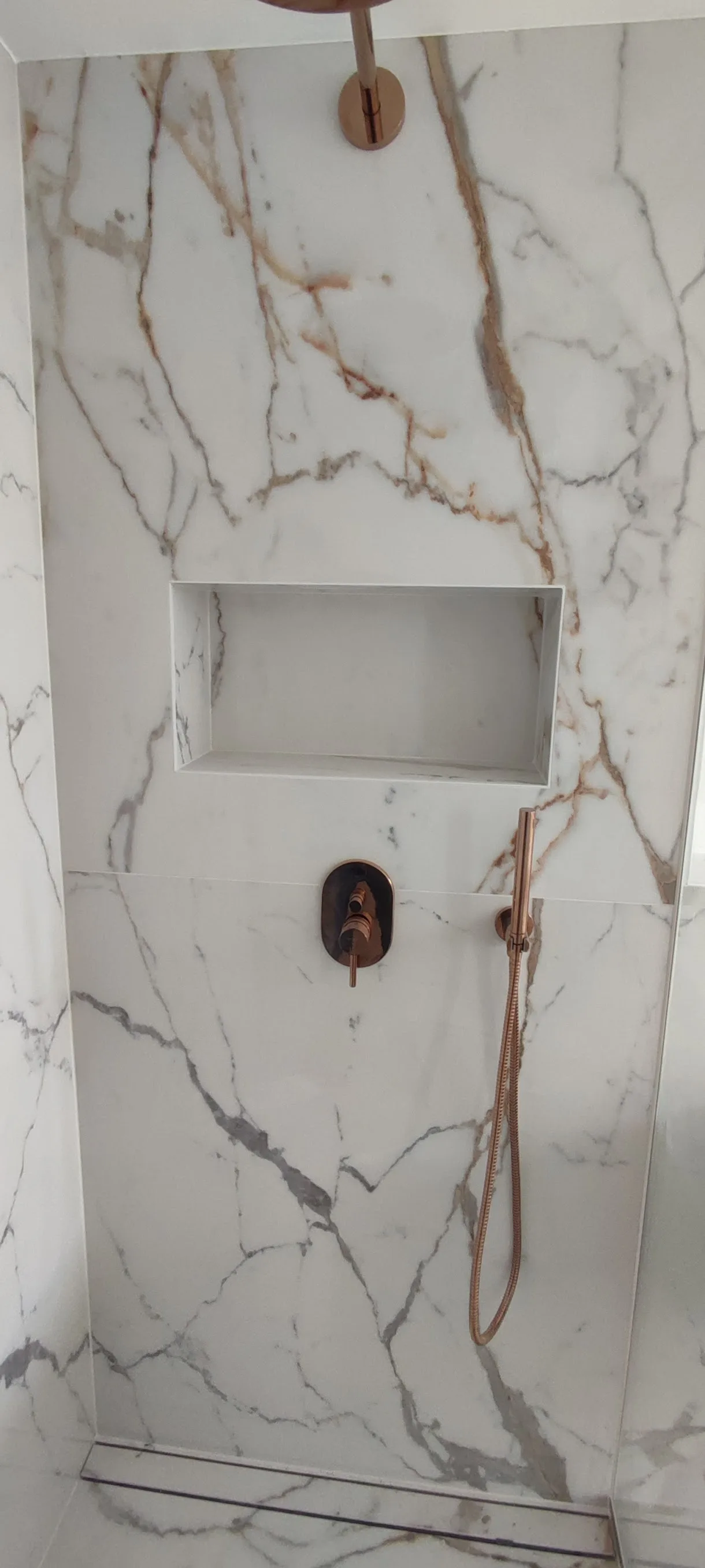Modernes Badezimmer mit marmorierter Fliesenwand und Duschbereich