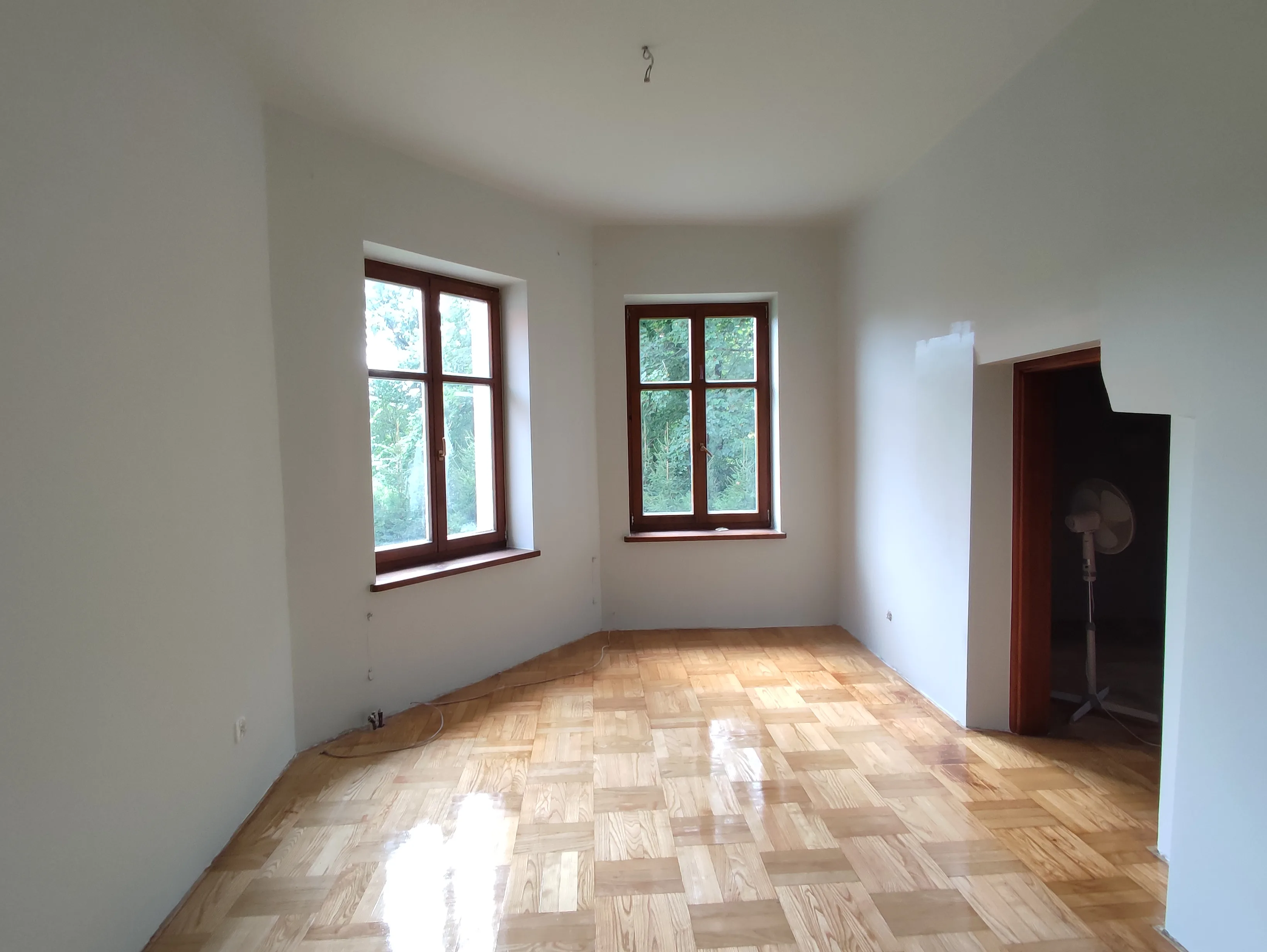 Renoviertes Zimmer mit Parkettboden und großen Fenstern