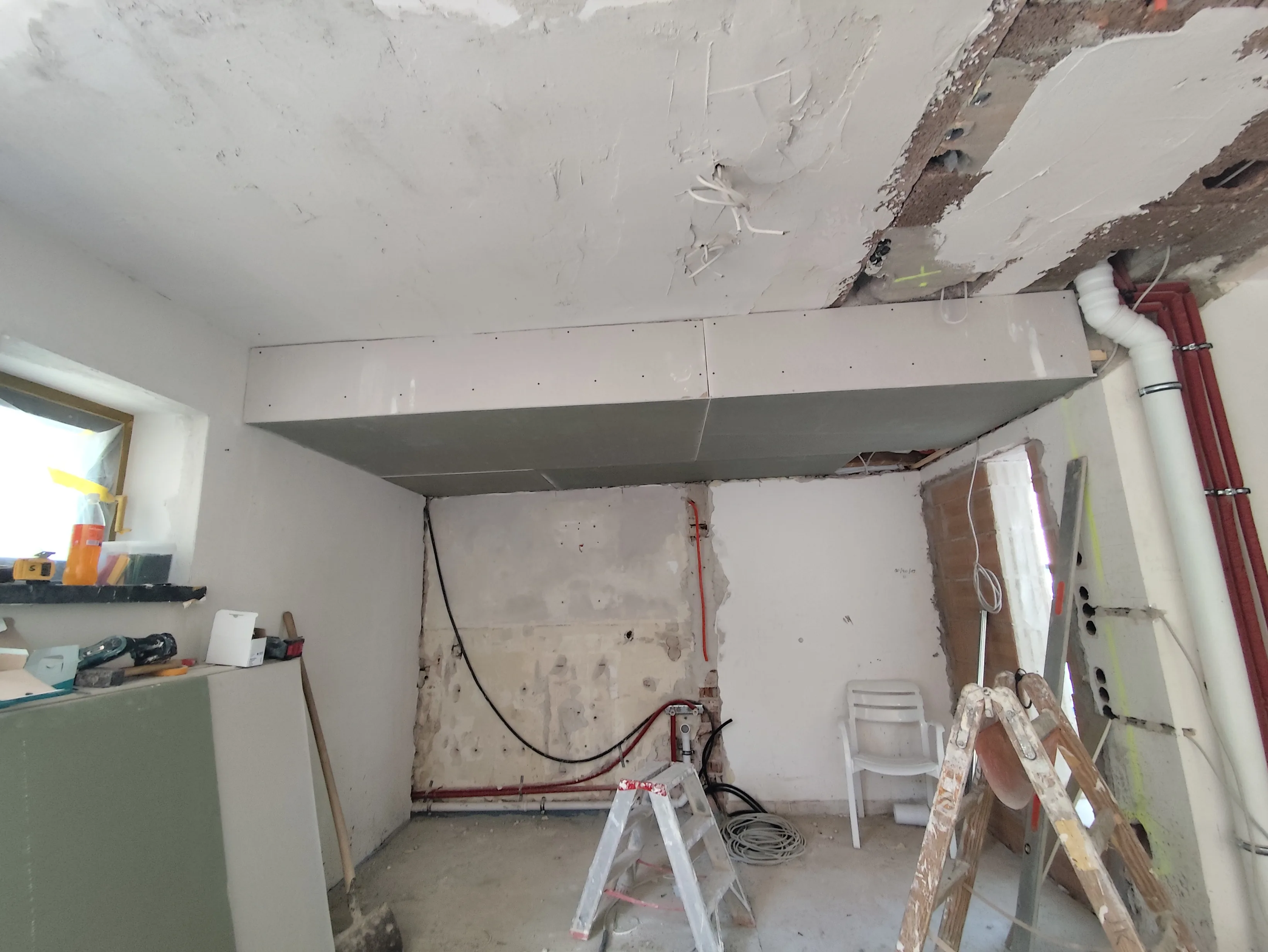 Trockenbauarbeiten an einer Decke mit Gipskartonplatten in einem renovierungsbedürftigen Raum