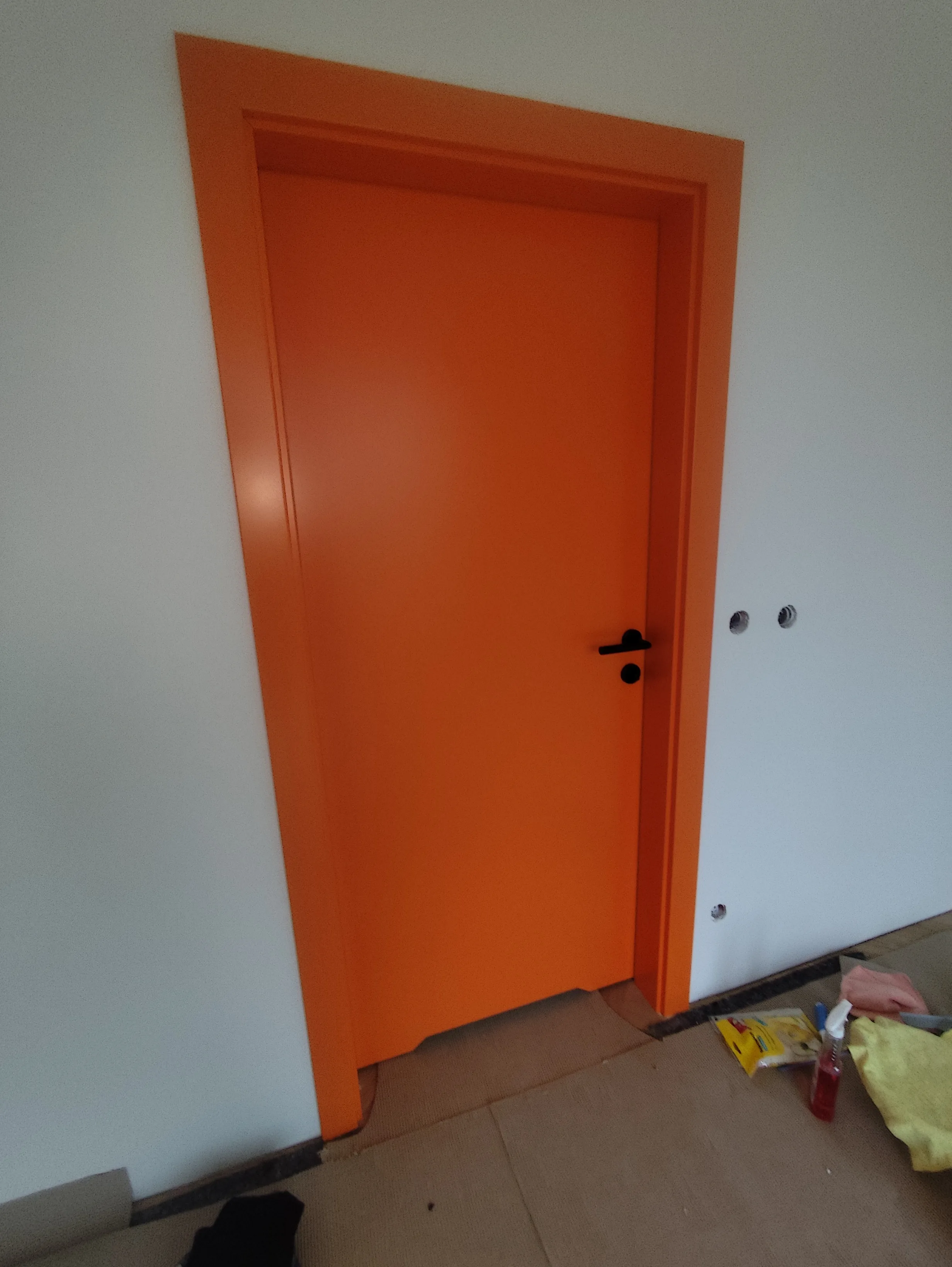 Orange Tür in einem renovierten Raum mit hellem Wanddesign