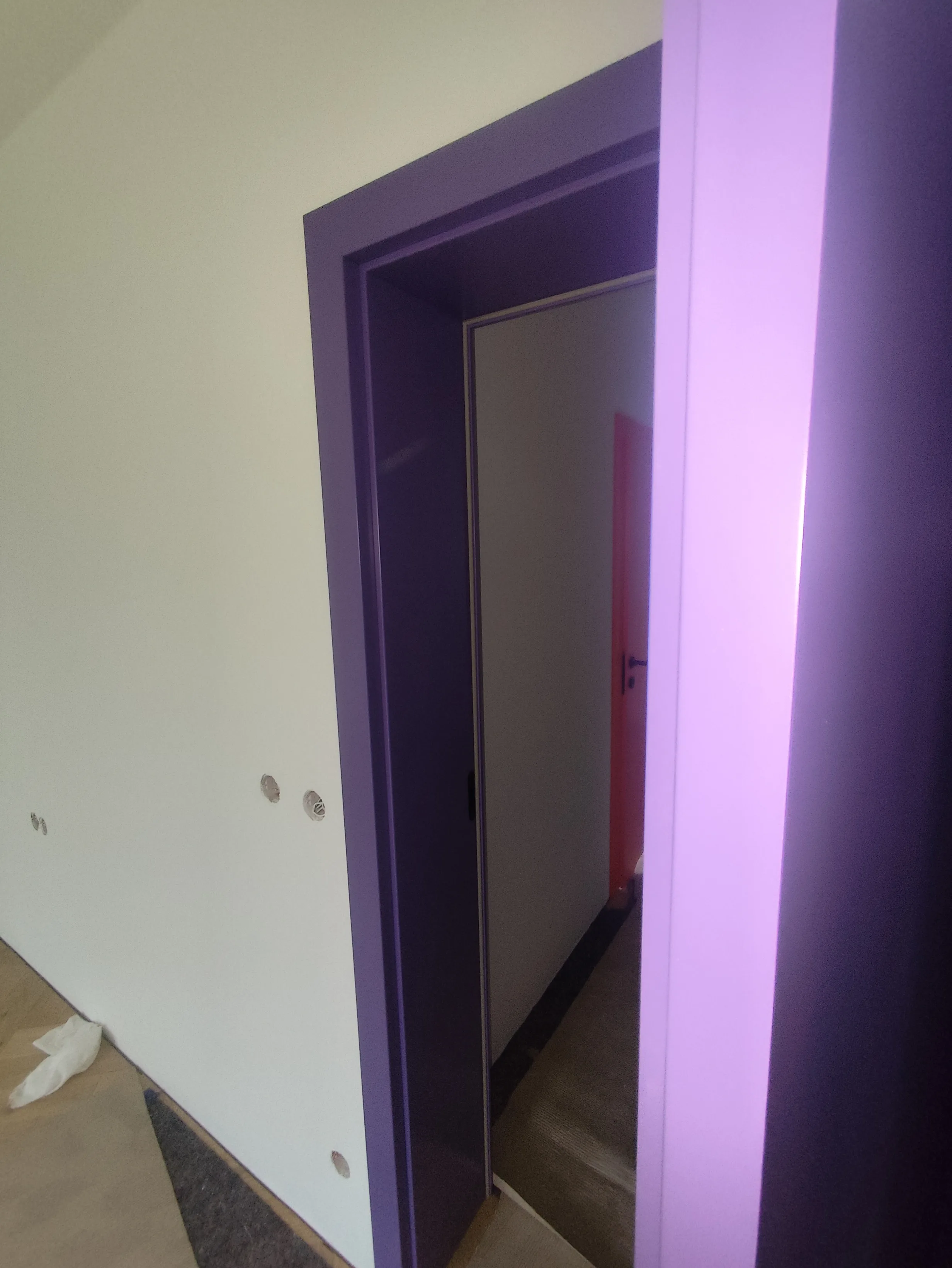 Sicht auf einen modern gestalteten Türrahmen in lila Farbe mit einem offenen Raum dahinter