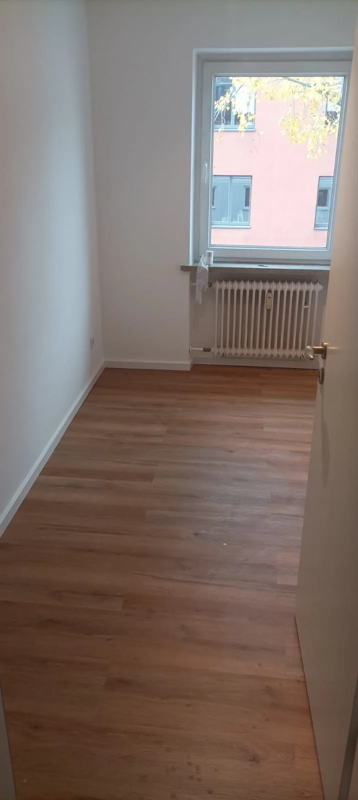Neubauzimmer mit Laminatboden und Fenster zur Straße
