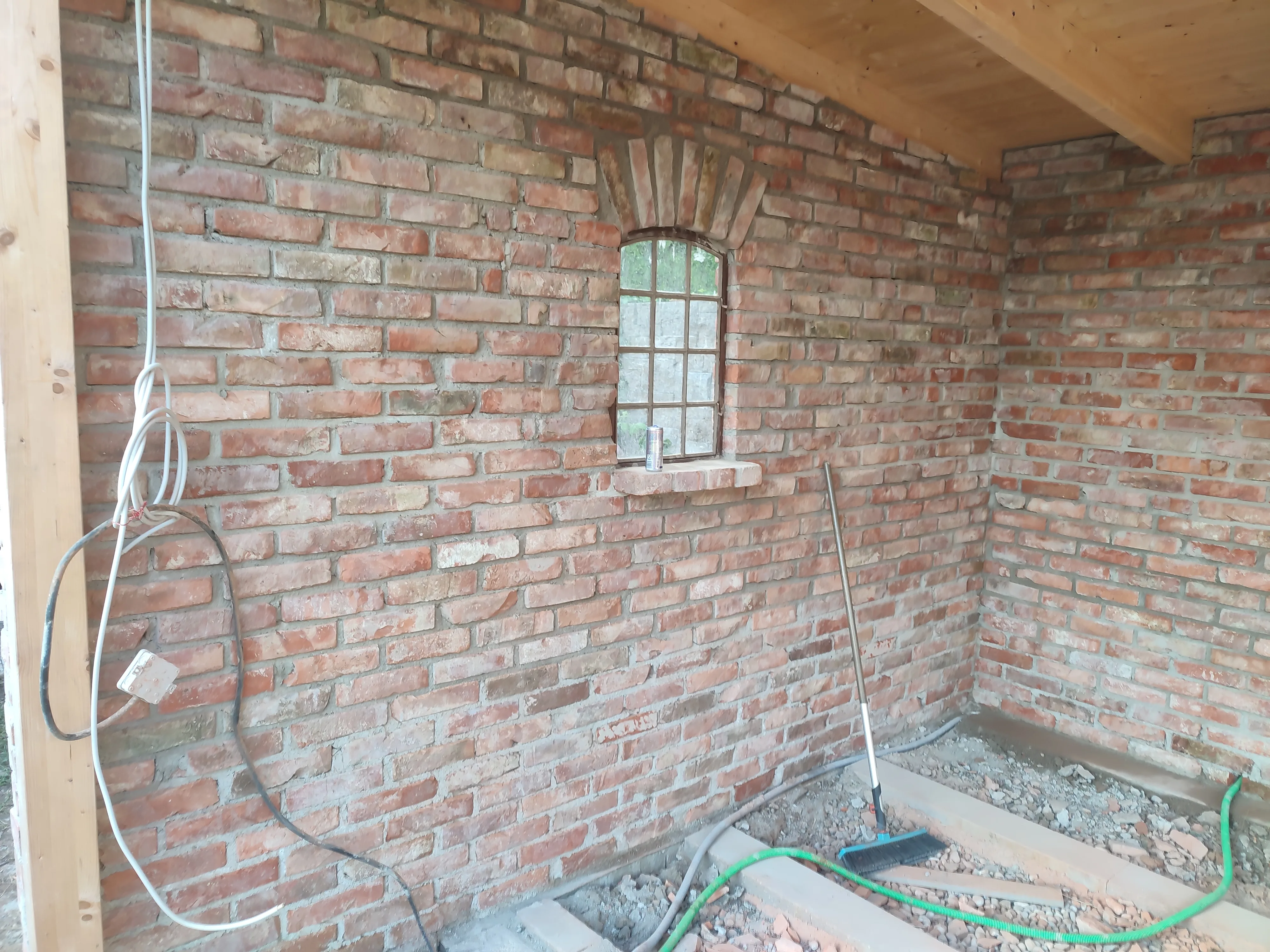 Sicht auf eine Ziegelwand mit Fenster und Holzdeckenkonstruktion