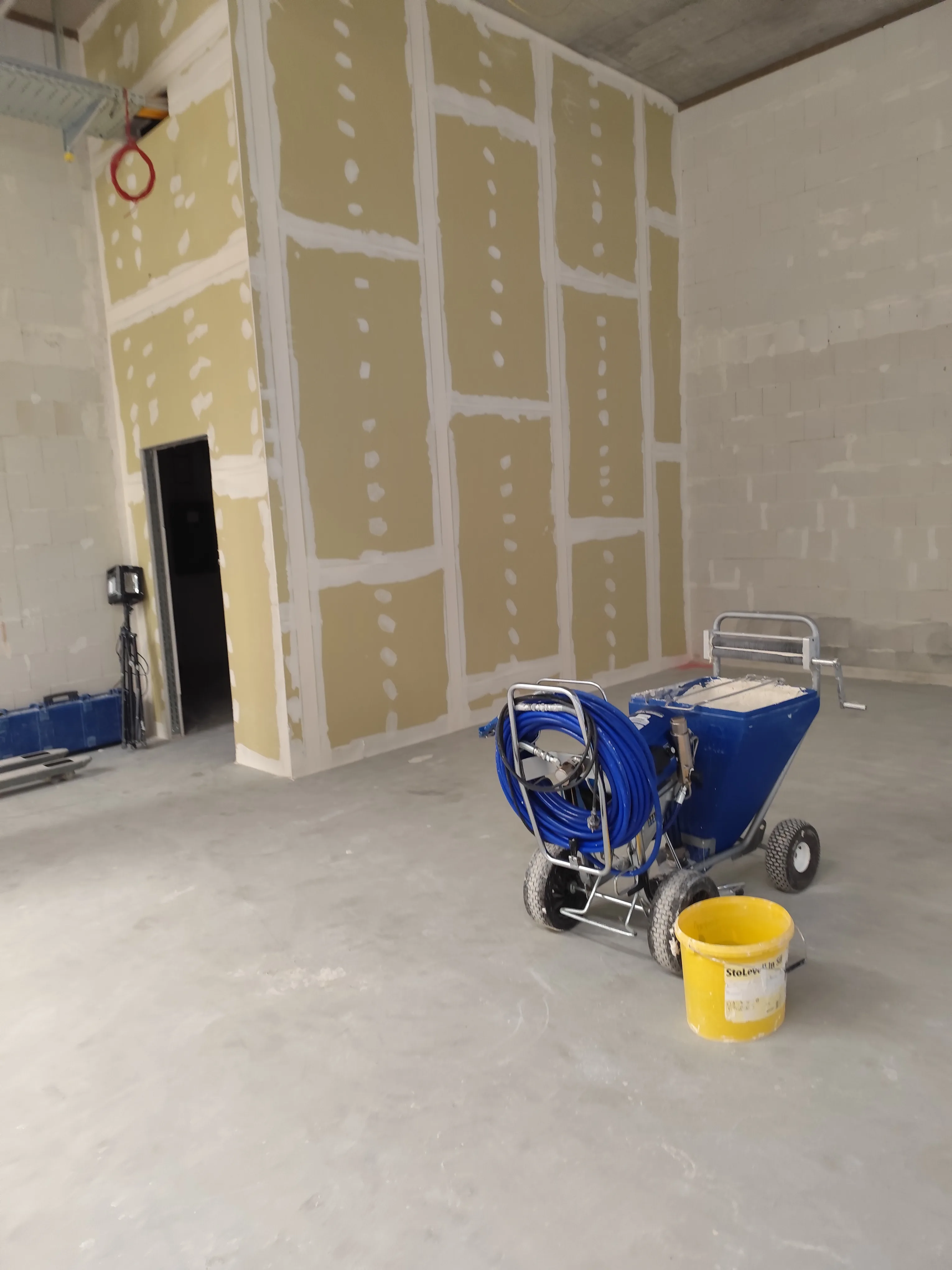 Baustelle mit Trockenbauwänden und Verputzmaschine im Vordergrund
