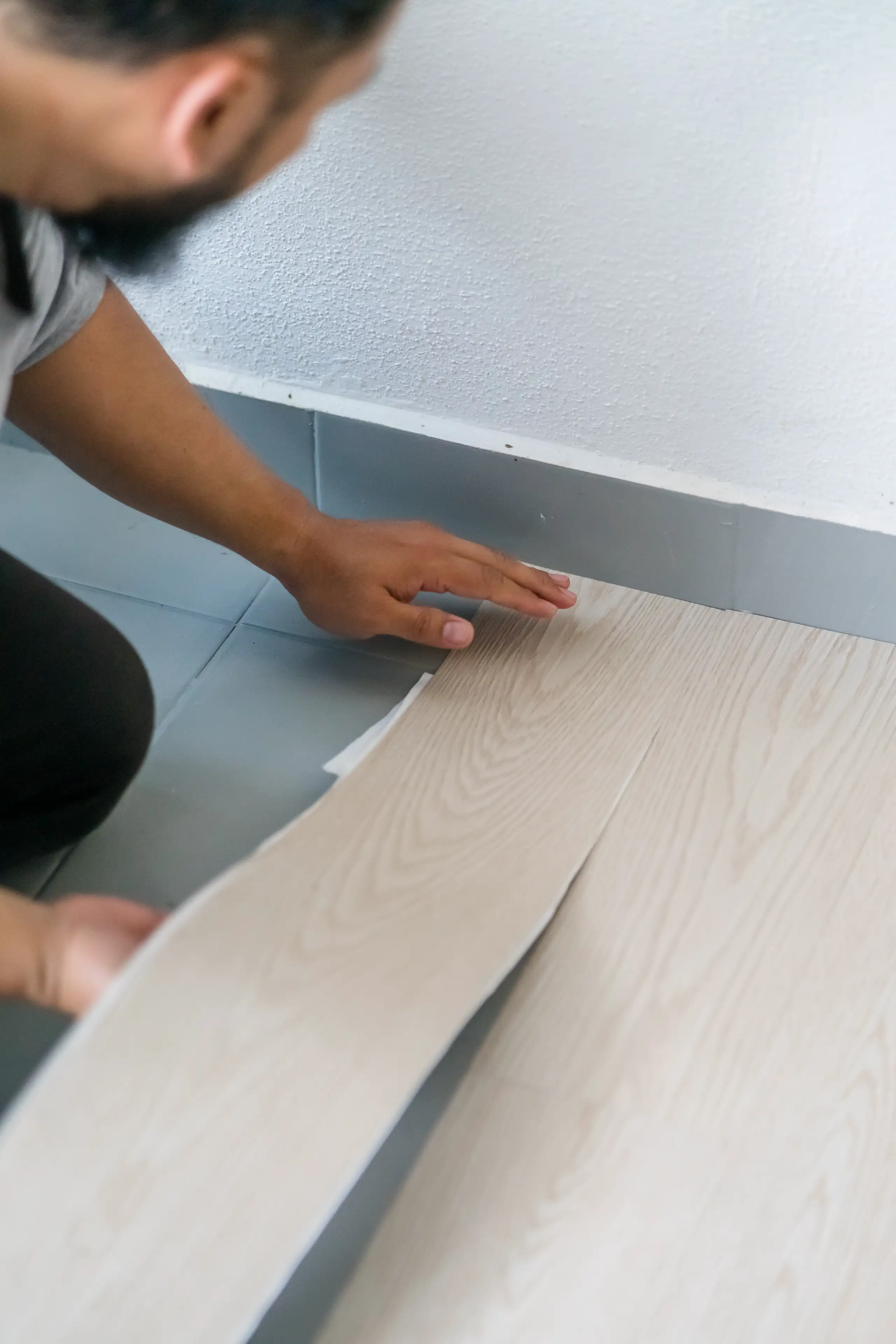 Ein Handwerker verlegt Laminatboden in einem Wohnraum