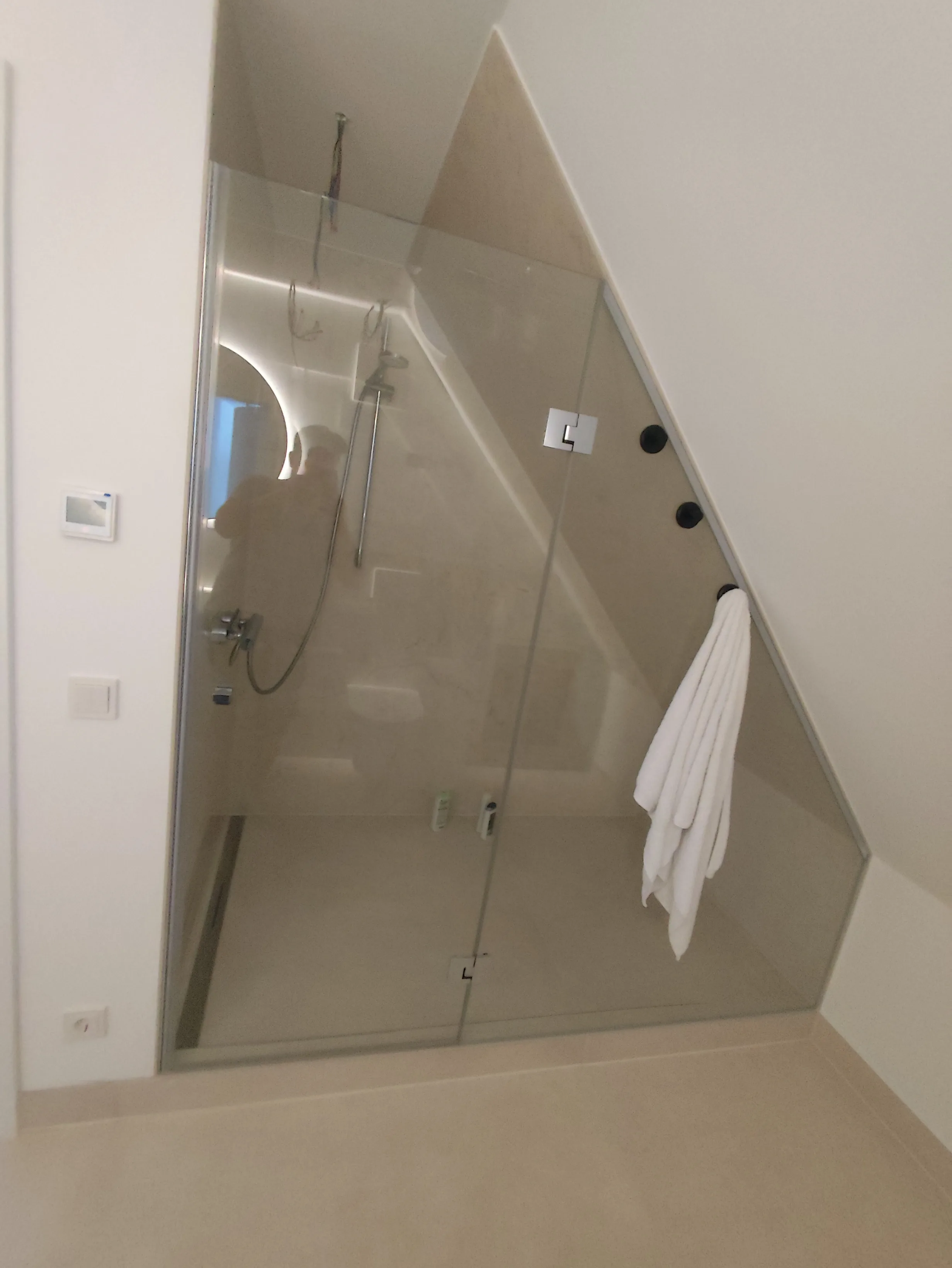 Moderne Duschkabine mit Glaswand in einem schrägen Raum, elegant und funktional gestaltet