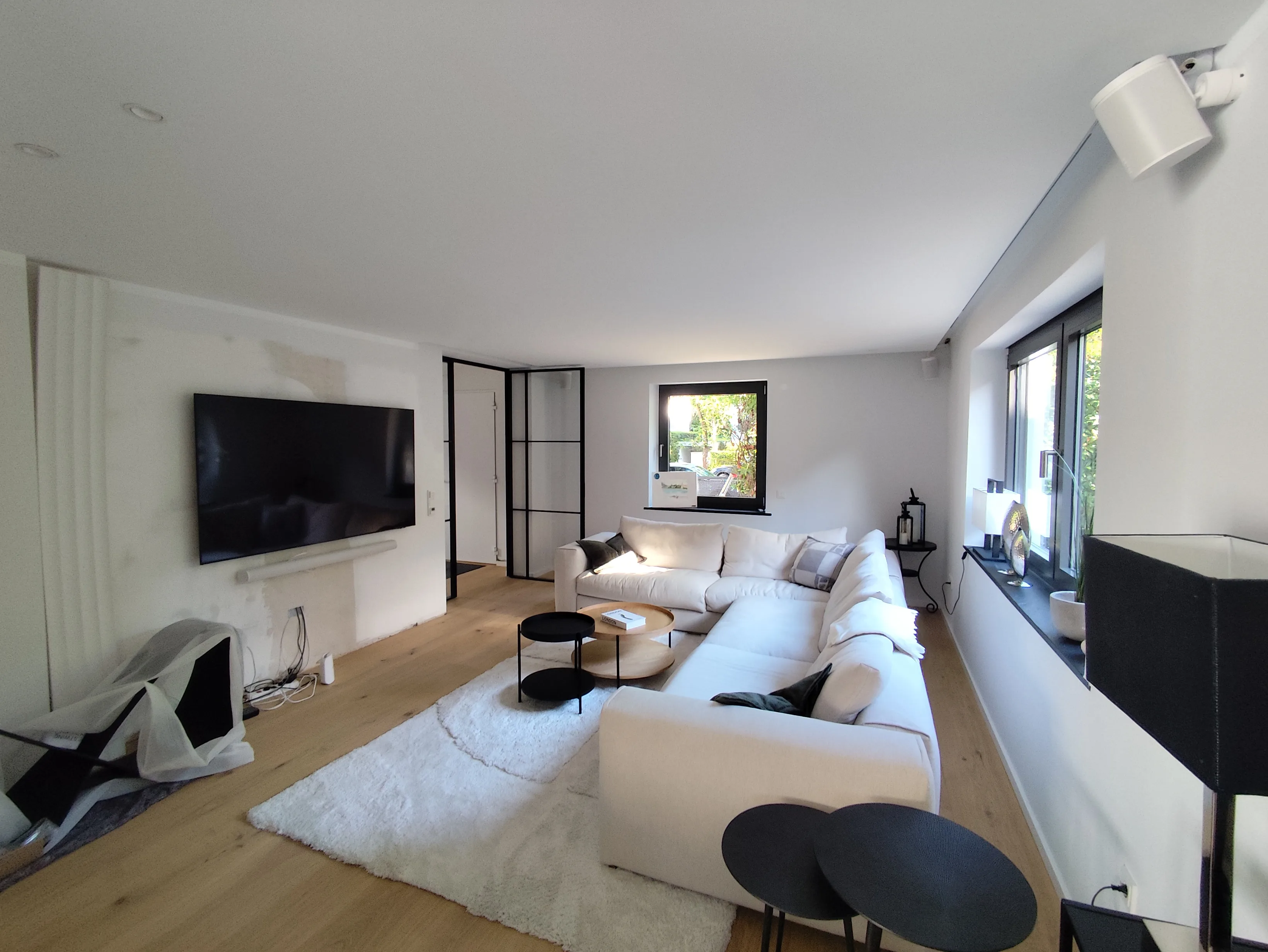 Modernes Wohnzimmer mit bequemer Couch, TV und großen Fenstern für Tageslicht