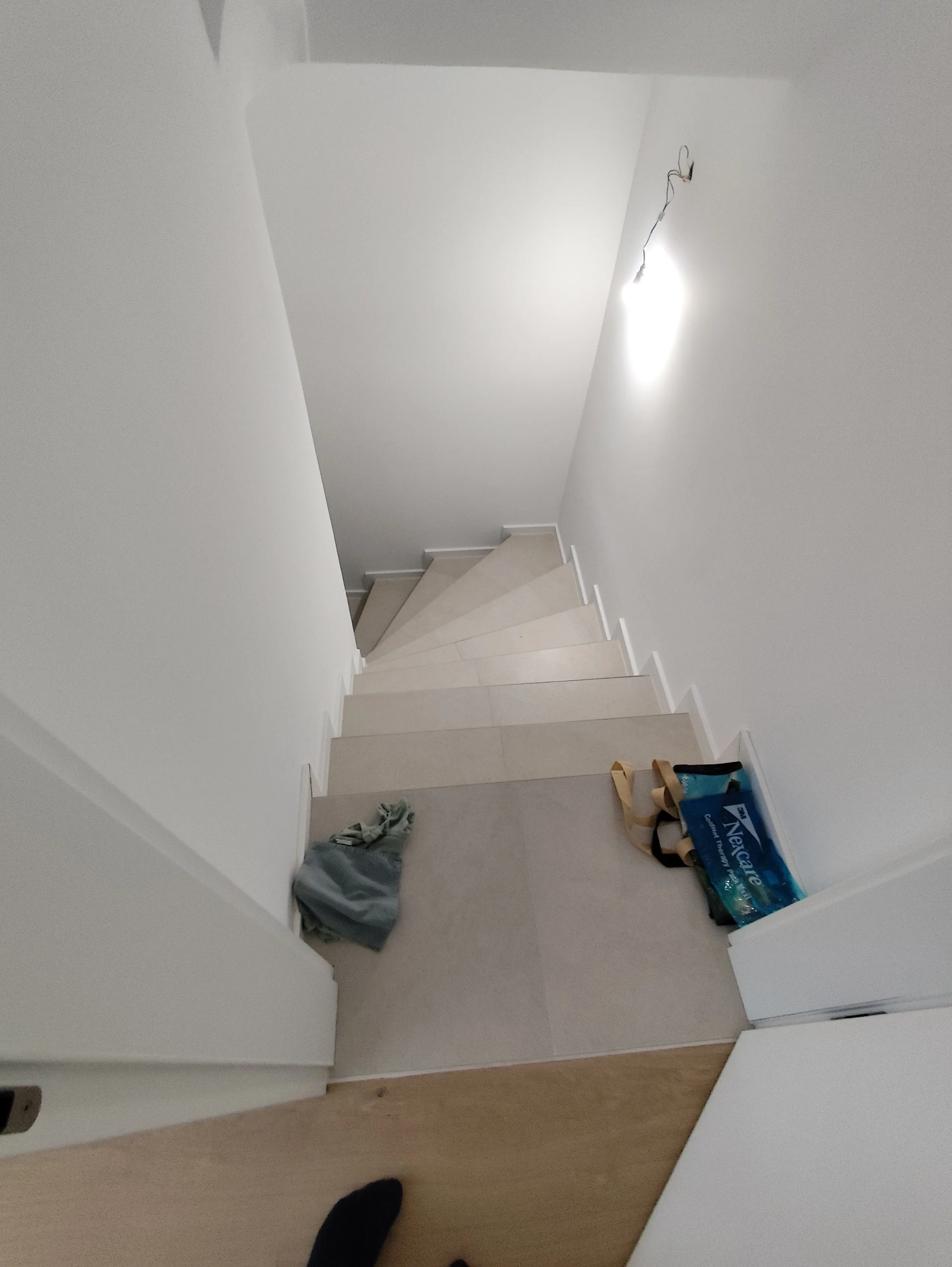 Treppe mit hellem Fliesenbelag und weißer Wand, ideal für Renovierungsarbeiten